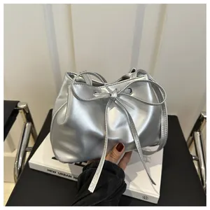 Detailed shot of silver drawstring bucket bag featuring a decorative bow and metallic finish