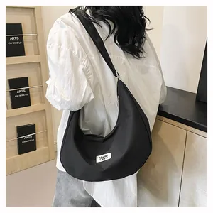 Rear view of a black crescent nylon crossbody bag on a model in a minimalist setting