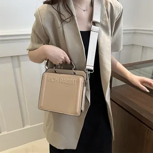 Minimalist beige tote bag with Rich Rabbit lettering and wide woven shoulder strap