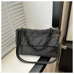 Close-up of quilted denim shoulder bag with bold black chunky chain and adjustable strap