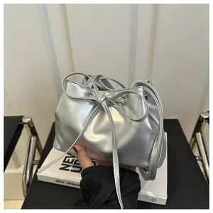 Detail of a silver metallic drawstring bucket bag featuring a decorative bow on the front