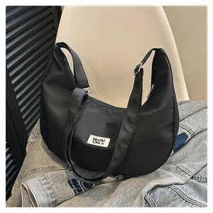 Detail of black waterproof nylon hobo bag with zip closure and woven brand label