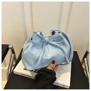 Close-up of light blue drawstring bucket bag featuring soft pleated texture and bow detail