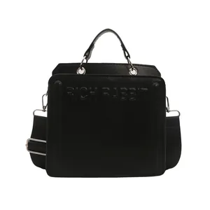 Minimalist black tote bag with Rich Rabbit embossed text and wide shoulder strap