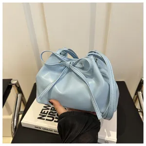 Close-up of light blue bucket bag featuring a large bow and drawstring closure