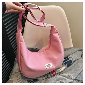 Detailed view of pink nylon crescent bag with adjustable strap and brand woven label