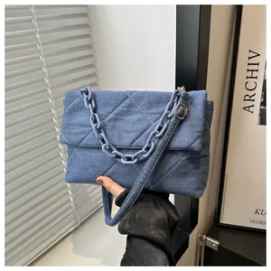 Detailed view of quilted denim handbag with matte blue chain strap and adjustable strap