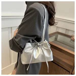 Detail of silver metallic bucket bag featuring bow drawstring and sleek shoulder strap