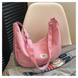 Pink waterproof nylon hobo bag featuring adjustable shoulder strap and brand label detail