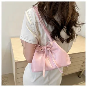 Detail of soft pink PU leather shoulder bag with drawstring bow and smooth glossy finish
