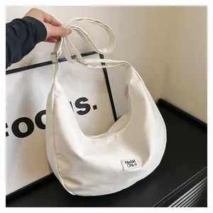 Detail view of white waterproof nylon crescent bag with adjustable strap and brand patch