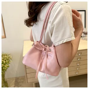 Detail of pink drawstring bucket bag with bow accent shown on model in cozy setting