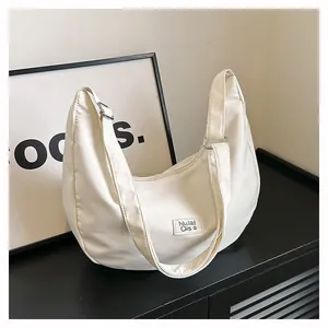 Detail of white nylon crescent hobo bag featuring a minimalist brand label and strap