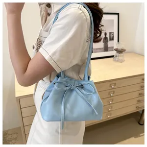 Detail of light blue drawstring shoulder bag with bow design and double straps