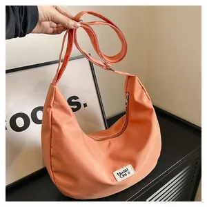 Close-up of bright orange nylon hobo bag with zip closure and white logo tag