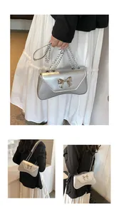Detailed view of silver metallic shoulder bag with 3D bow hardware and chain strap