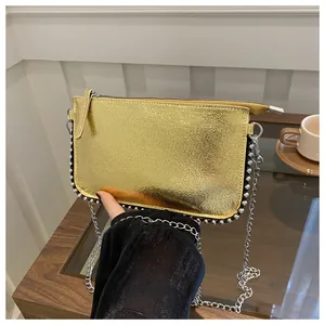 Nahaufnahme der goldenen Handtasche mit silbernen Nieten und Kettenriemen auf dem Tisch
