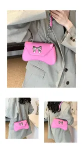 Detail of pink leather handbag featuring a silver bow metal buckle and chain strap