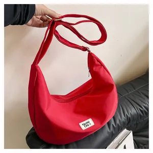 Detail of red crescent bag showing smooth zipper closure and adjustable shoulder strap