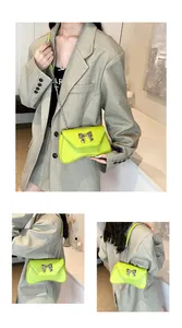 Detailed view of neon green crossbody bag featuring silver bow buckle and chain strap