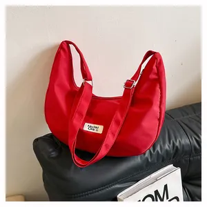 Detail of red nylon hobo bag showing adjustable strap and brand label on black leather
