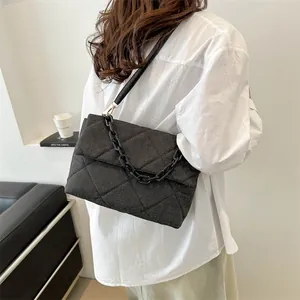 Quilted denim envelope bag with black chain strap and modern minimalist design