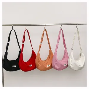 Row of colorful nylon crescent crossbody bags in black, red, orange, pink and white