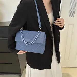 Blue denim quilted envelope bag with decorative chain and adjustable shoulder strap