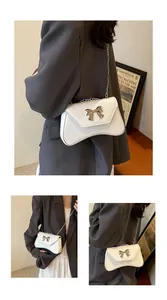 Detail view of white PU leather shoulder bag with silver bow clasp and chain strap