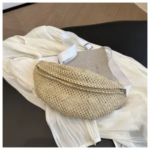 Detail of hand-woven straw chest bag with metal zipper and adjustable fabric strap