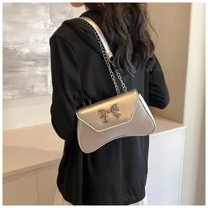 Silver metallic crossbody bag with chain strap and bow detail on a black dress