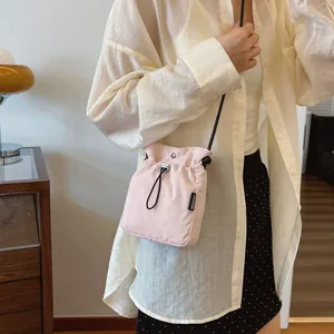 Rosa Nylon-Umhängetasche mit Kordelzug und schwarzem Riemen, getragen von einem Modell
