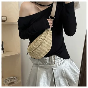 Close-up of woven straw chest bag with metal zipper and adjustable strap on a model