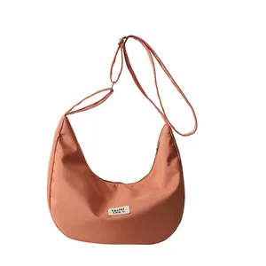 Waterproof nylon crossbody crescent bag in coral orange with adjustable shoulder strap