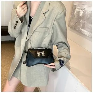 Detail of black PU leather shoulder bag with silver metal bow and chain strap