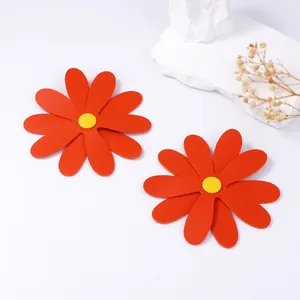 Macro shot of large orange PU leather daisy stud earrings with textured petals