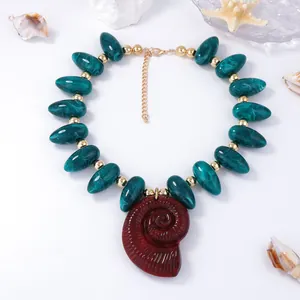 Détail macro du pendentif coquillage en résine et des perles marbrées avec métal