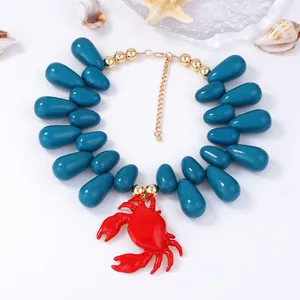Dettaglio della collana con perle verde acqua e ciondolo granchio con decoro mare