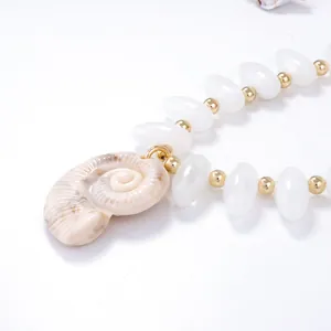 Détail du pendentif en forme de nautile avec perles blanches et perles dorées
