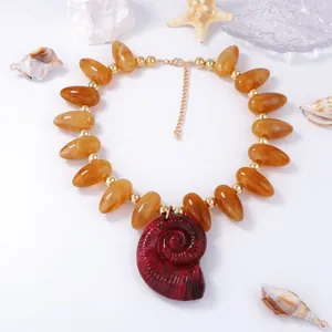 Détail macro du collier de perles ambrées avec grand pendentif nautile spirale rouge