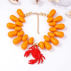 Dettaglio della collana di perle arancioni a goccia con ciondolo a forma di granchio rosso