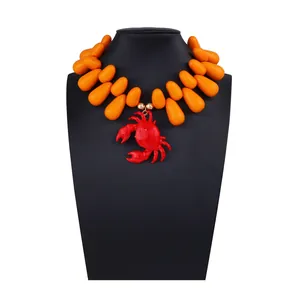 Dettaglio del pendente a granchio rosso su collana di grosse perle arancioni stile mare