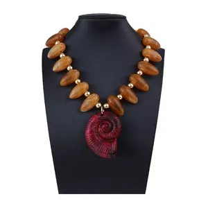 Détail du collier de perles ambrées avec grand pendentif conque rouge sur buste noir