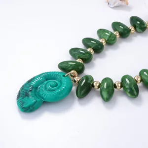 Détail du pendentif spirale vert menthe avec perles vert foncé à motifs d'eau et dorures