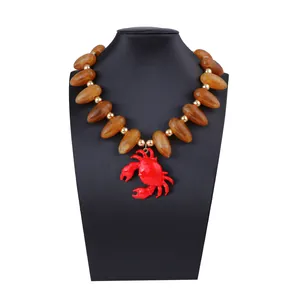 Détail d'un pendentif crabe rouge audacieux et de perles ambrées sur un buste noir