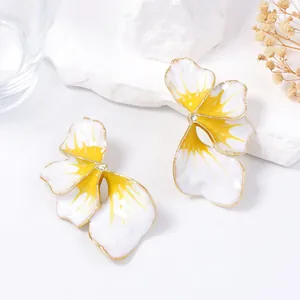 Dettaglio ravvicinato di orecchini a fiore in smalto bianco con centro giallo