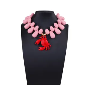 Dettaglio di perle a goccia rosa con ciondolo a forma di granchio rosso su supporto