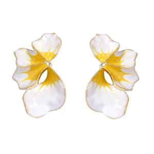 Dettaglio macro di orecchini a fiore in smalto con petali sfumati bianco e giallo
