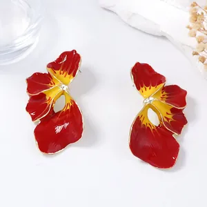 Dettaglio di orecchini bohémien a fiore rosso e giallo con bordi dorati