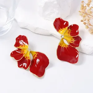 Dettaglio di orecchini a forma di orchidea in smalto rosso e giallo con bordi dorati
